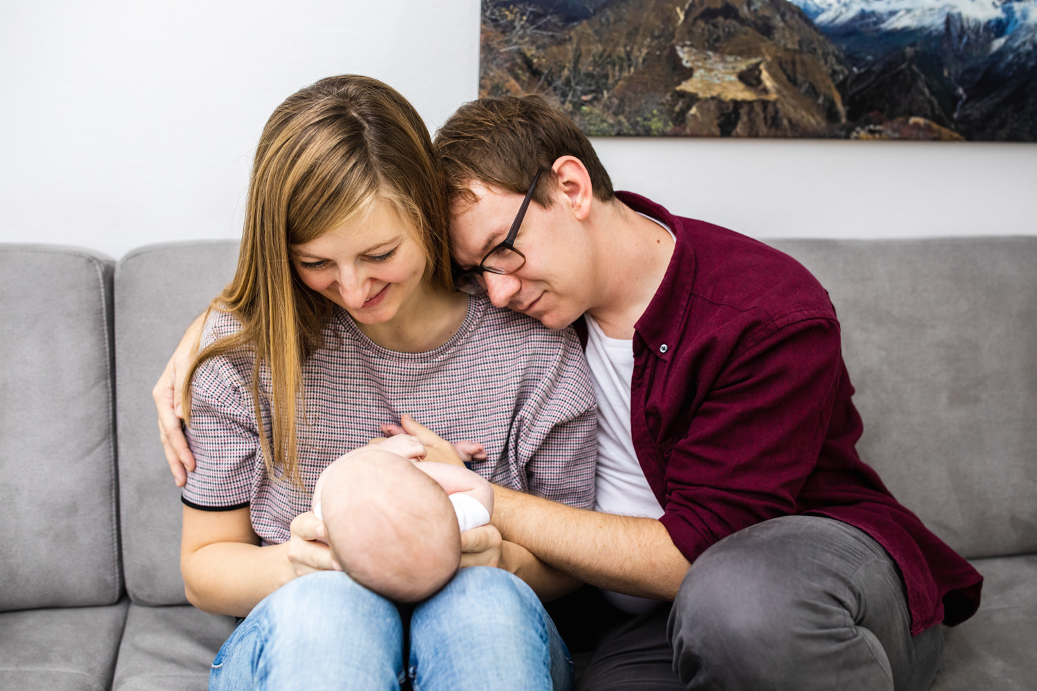 Eltern sitzen mit ihrem Baby auf dem Sofa - Homestory Fotoshooting - Fotograf Starnberg