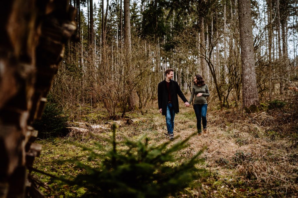 Babybauch - Schwanger - Paar läuft Hand in Hand durch den Wald