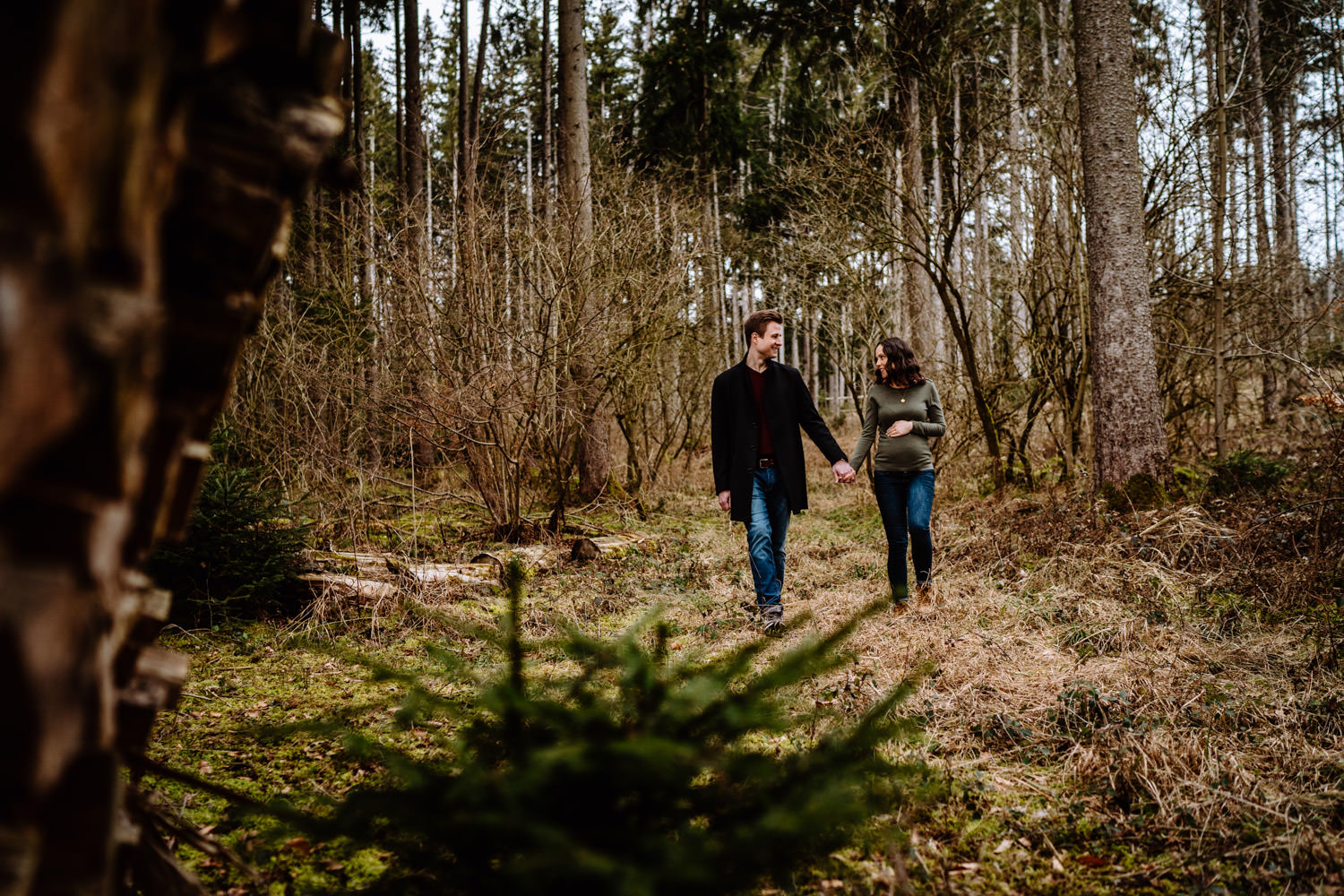 Babybauch - Schwanger - Paar läuft Hand in Hand durch den Wald